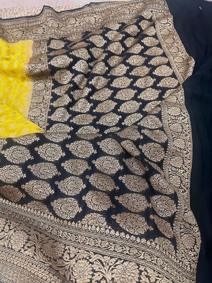 A classic black and yellow combination in pure Banarasi Kadi georgette. The rich weaving on the pallu and border makes this a timeless piece.