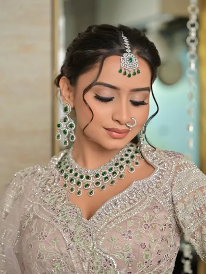 A serene, eyes-closed portrait that draws attention to the beautiful eye makeup and the sparkle of the diamond necklace and maang tikka.