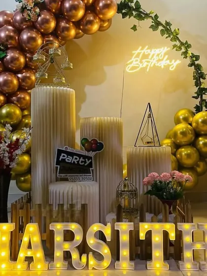 A sophisticated gold and rose gold balloon arch with a neon sign and marquee letters.