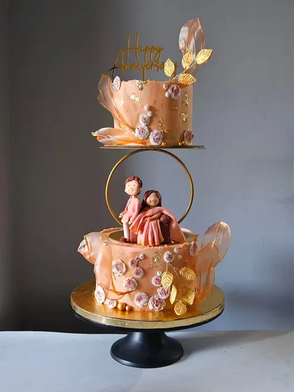 To celebrate a special anniversary, I crafted this elegant two-tier cake featuring personalized figurines of the couple. The design is enhanced with delicate rice paper sails, hand-painted gold leaf accents, and soft floral details, creating a romantic and sophisticated centerpiece.