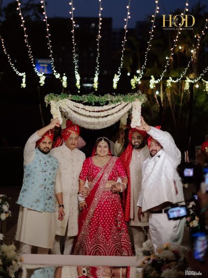 The bride under a traditional floral chadar, held by her family, a beautiful and emotional moment during the wedding ceremony.
