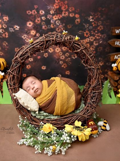 As sweet as honey. This newborn is dressed as a tiny bee, sleeping in a hive-like nest surrounded by sunflowers. It is a wonderfully sweet and charming theme.