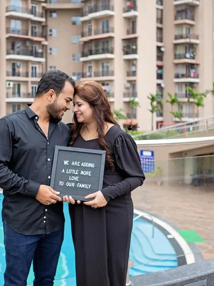 "We are adding a little more love to our family." This couple portrait by the pool, dressed in simple black, is a sweet and modern way to announce their pregnancy.