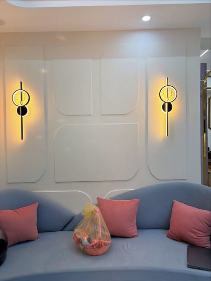 A close-up of the wall behind the sofa, featuring modern geometric molding and stylish wall sconces that add a layer of sophistication.