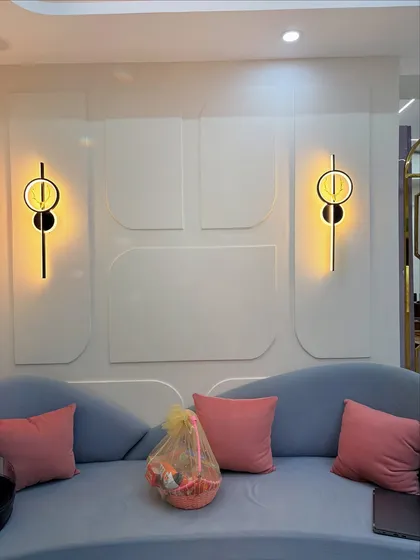 A close-up of the wall behind the sofa, featuring modern geometric molding and stylish wall sconces that add a layer of sophistication.