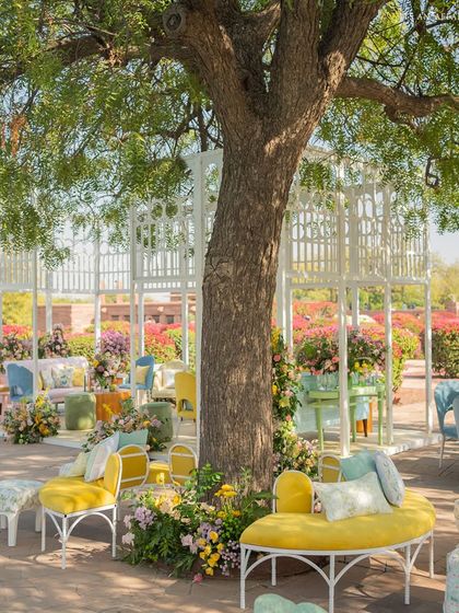 A curved yellow bench wraps around a large tree, creating an organic and inviting seating area within the garden.