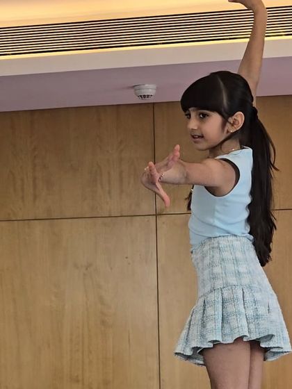A young girl strikes a graceful pose. Our gymnastics parties inspire confidence and body awareness, allowing kids to express themselves through movement.
