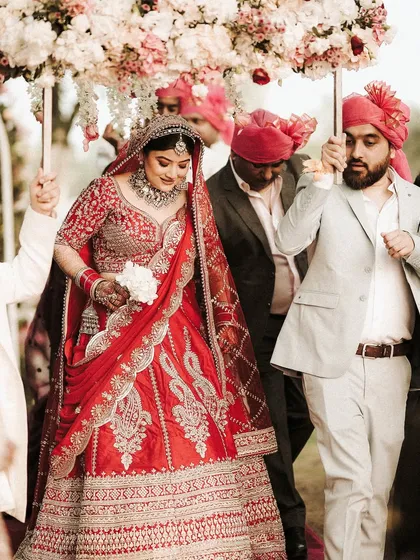 The bride's grand entrance under a beautiful floral canopy. Her makeup is designed to make a statement, ensuring she looks like a queen as she walks towards her new beginning.