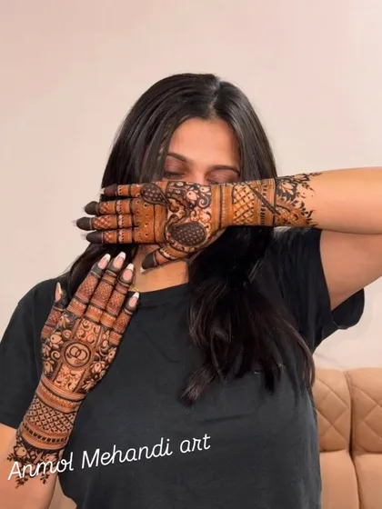 A candid shot of a client admiring her intricate henna design, which includes personalized initials.