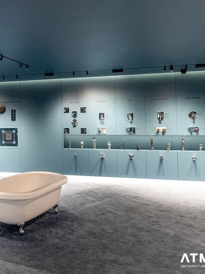 A freestanding bathtub serves as a sculptural element against a wall of meticulously organized faucet displays. This juxtaposition of a large statement piece with smaller detailed items creates visual balance in the showroom.