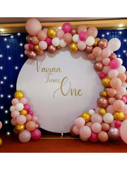 A chic first birthday celebration for Vairaa, using a beautiful rose gold, pink, and gold balloon garland on a custom circular backdrop. The large foil '1' balloon adds the perfect touch.