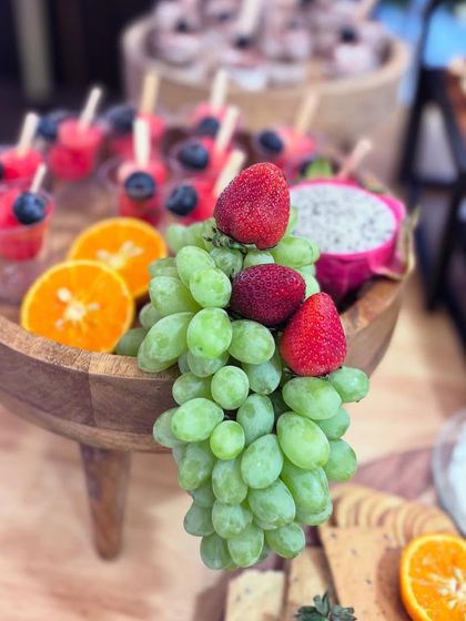Freshness is key. This tiered fruit display features lush green grapes, sweet strawberries, and individual fruit cups with watermelon and blueberries, offering a light and healthy option for guests.