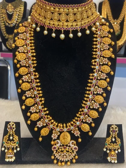 This Kasu Malai (coin necklace) set is paired with a temple choker, offering a layered and opulent look. The coins feature goddess engravings.