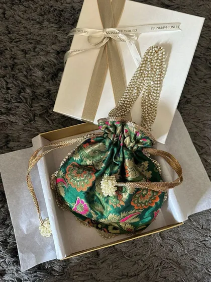 A beautiful brocade potli being placed in an elegant gift box. This is an example of how I package individual items to make them feel like a luxurious present.