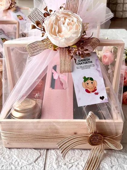 Ganesha's grace in a tiny package. A beautiful hamper for Ganesh Chaturthi, featuring sweets, a diya, and other thoughtful items in a wooden crate.