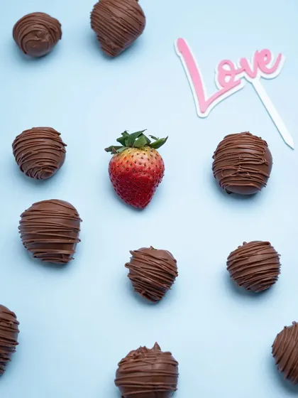 A pattern of chocolate-covered strawberries with a single fresh strawberry. This artistic composition is visually interesting and great for social media.