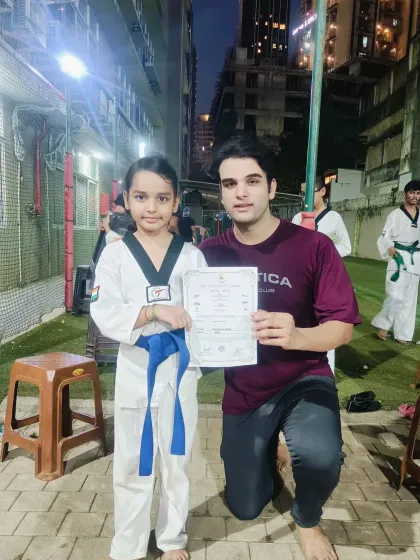 A proud moment for this young student as she receives her blue belt certificate. Her hard work in class has paid off, and she's ready for the next level.
