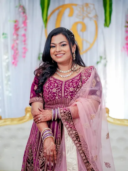 A full-length shot of this beautiful bride in a deep magenta lehenga for her reception. Her makeup is classic and elegant, with a focus on defined eyes and a radiant complexion.