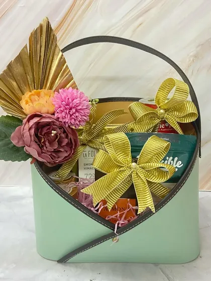 An elegant mint green envelope basket filled with goodies, making for a stylish Mother's Day surprise.