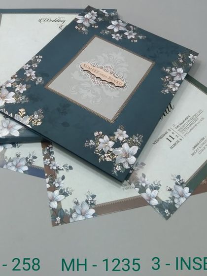 A dark teal invitation set featuring a border of white flowers. The design is elegant and modern, with three inserts to cover all your wedding events.