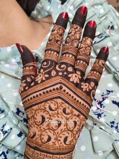 A close-up of a detailed back-of-hand design with swirling leaf patterns.