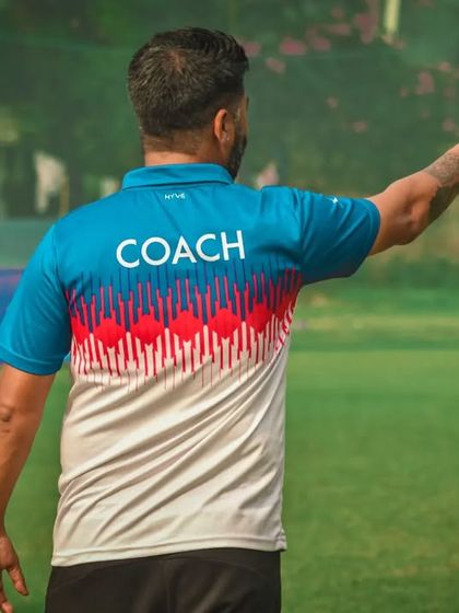 A coach points and gives instructions to his team from the back, his guidance shaping the play on the field.