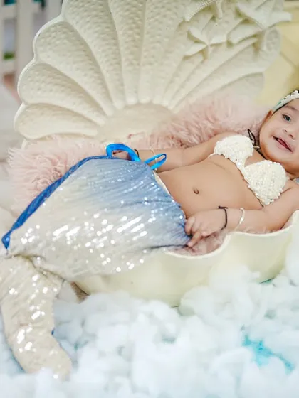 A relaxed and happy portrait of the baby girl in her sparkling mermaid costume.