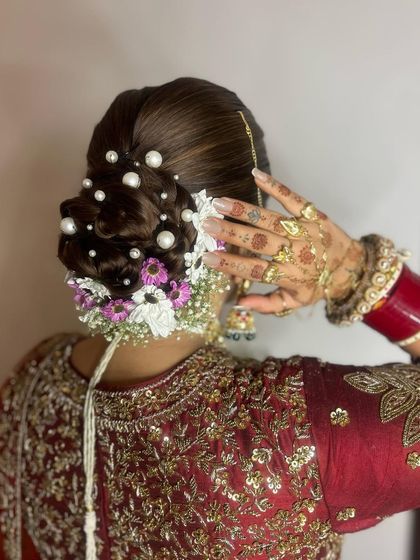 A side view of Akanksha's intricate bridal bun, showing her beautiful henna and jewelry.
