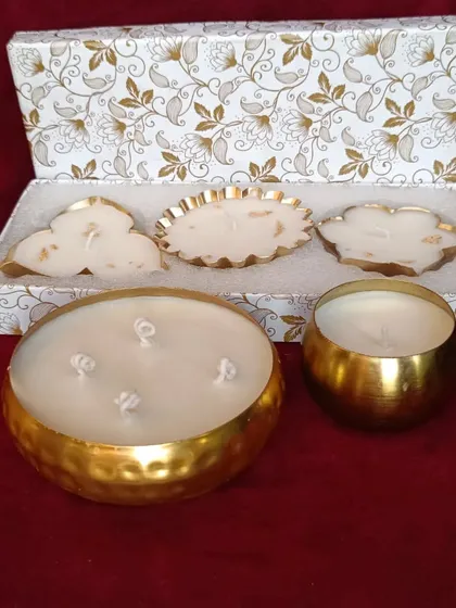 A complete Diwali gift hamper, featuring large and small golden urli candles and a set of three smaller decorative urlis.