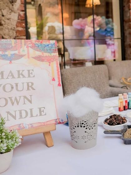 A close-up of the 'Make Your Own Candle' station sign. The setup includes everything guests need to create their own unique and fragrant party favor.
