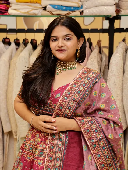 A smiling client in a pink printed lehenga, ready for her event.