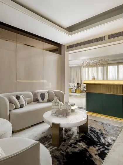 This lounge and bar area are designed to flow into one another, creating a perfect setting for evenings with friends. A custom green and gold bar is complemented by a lounge area with a sculptural floor lamp and soft, neutral-toned sofas.