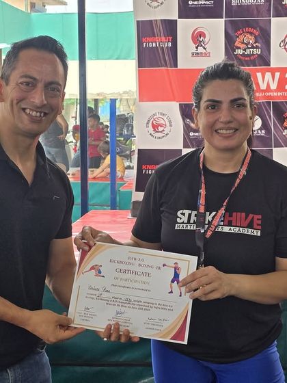 A female competitor receives her certificate, representing the strength and skill of the women at StrikeHive.