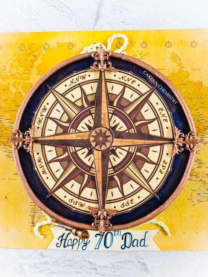 The top view of the nautical compass cake. The compass itself is an edible print, but it's framed with intricate, hand-piped details to give it dimension and a vintage feel.