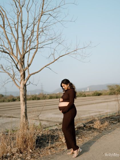 A simple, elegant portrait against a minimalist outdoor landscape. The focus is all on her beautiful silhouette and the bond with her baby.
