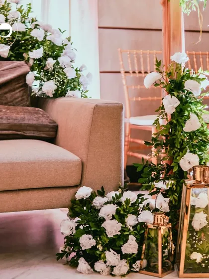 A wider view of the Roka seating area, showing the interplay of fresh florals, warm lighting from gold lanterns, and elegant Chiavari chairs in the background.