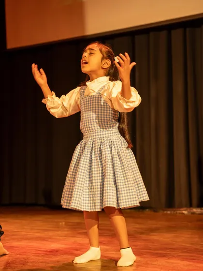 A young actress singing her heart out on stage. We encourage all forms of expression, including musical performance.