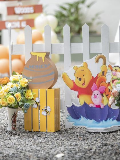 A collection of Pooh and friends on an umbrella prop, placed next to a honey pot. These small scenes add so much character to the decor.