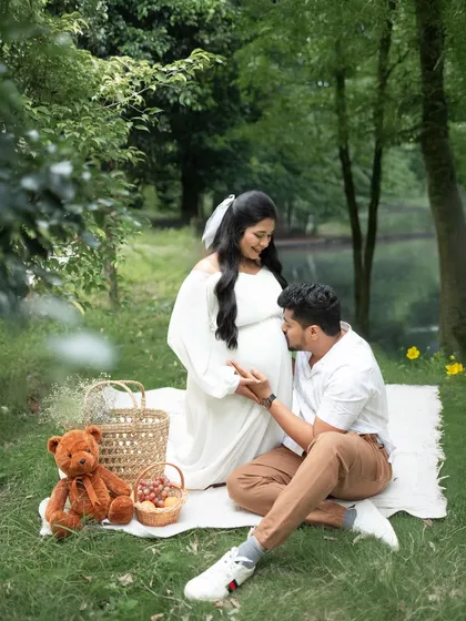 A styled picnic shoot is a wonderful way to create a relaxed and personal story. Here, an expecting couple enjoys a serene moment in nature, complete with a teddy bear and other sweet props.