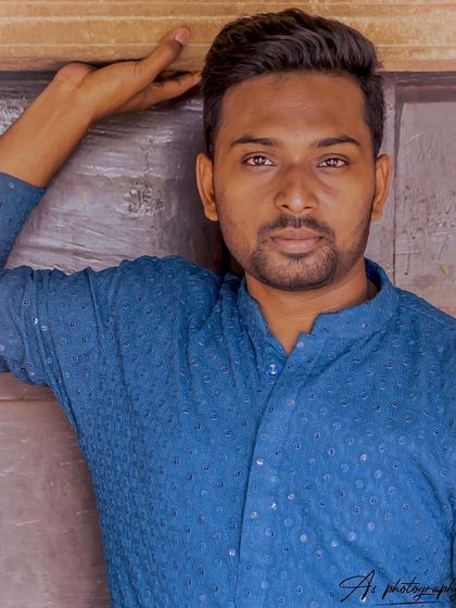 A close-up portrait in a traditional blue kurta. The focus is on the model's direct and engaging expression, highlighting his suitability for ethnic wear modeling.
