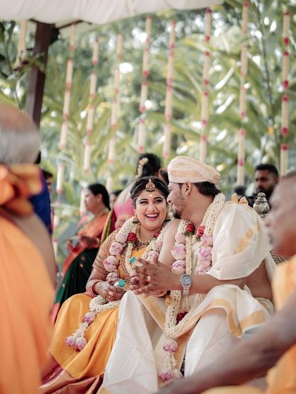 The couple sharing a happy moment during their South Indian wedding ceremony. The traditional attire and the joyful expressions capture the essence of the celebration.