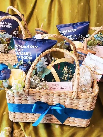 A glimpse of a bulk order of Rakhi hampers ready to go. These kauna grass baskets are filled with popcorn, sippers, and other goodies, each decorated with a blue ribbon.
