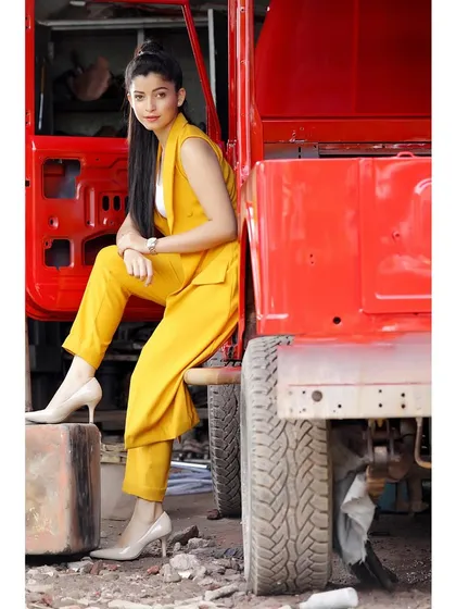 An industrial-chic fashion shoot. The contrast between the bright yellow power suit and the rugged red jeep creates a visually arresting image.