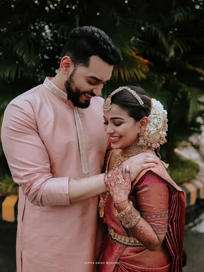 A tender moment between the bride and groom, his hand on her shoulder, their smiles full of love.