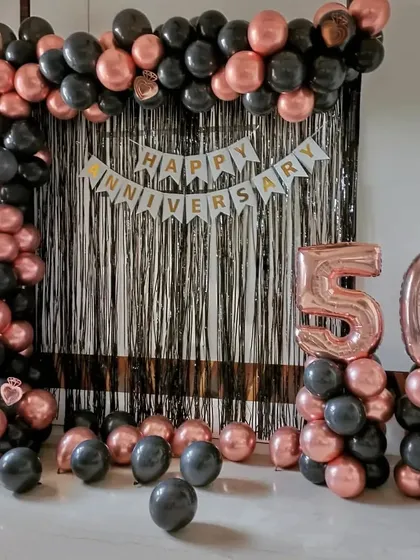 Celebrating a golden jubilee with a 50th anniversary decoration. This setup uses a sophisticated black and rose gold color scheme with a foil curtain backdrop and large marquee numbers.