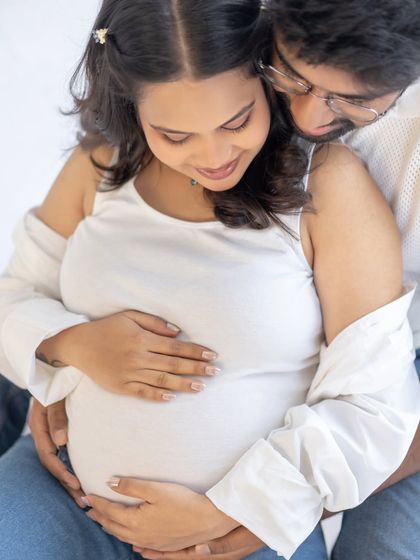 A tender close-up of the couple. This image focuses on their hands cradling the bump and their gentle expressions, creating a feeling of warmth and intimacy.
