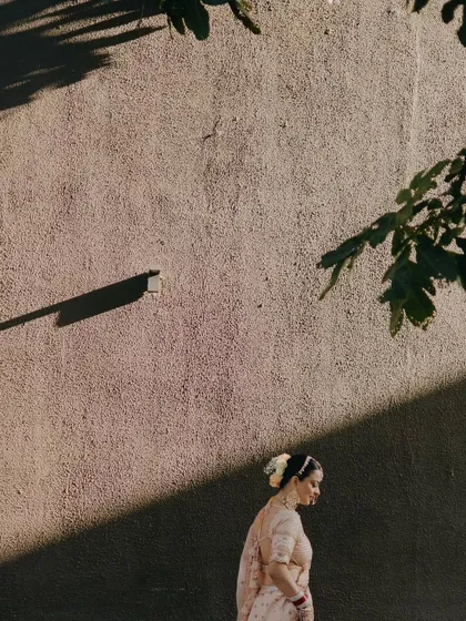 An artistic shot of the bride walking in the shadows, with only a sliver of sunlight illuminating her, creating a dramatic and thoughtful portrait.