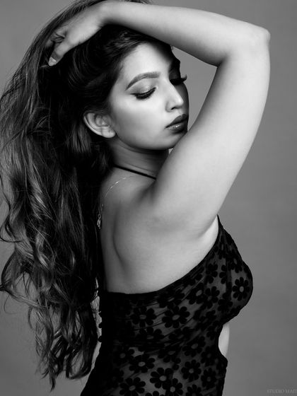 A soft, black and white portrait focusing on the texture of the model's hair and the delicate floral pattern of her dress.