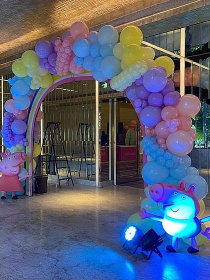 Another view of the lit-up rainbow arch, with Peppa and George cutouts on either side to welcome the little guests.