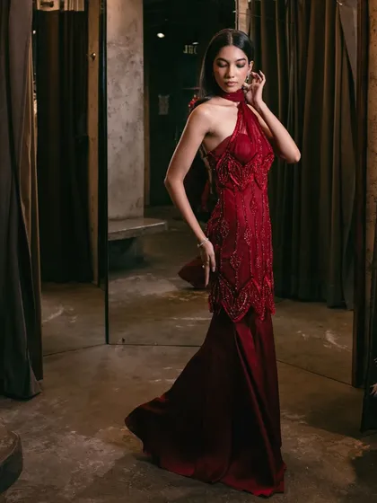 A breathtaking crimson-hued sharara, adorned with exquisite embellishments and featuring a striking one-shoulder design with an attached drape.